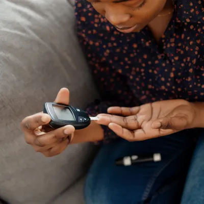 A Woman Tests Her Blood Sugar with a Finger Prick Glucose Device