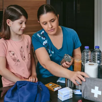 A Mother Looks Over a First Aid Kit with Her Daughter on the Kitchen Table.