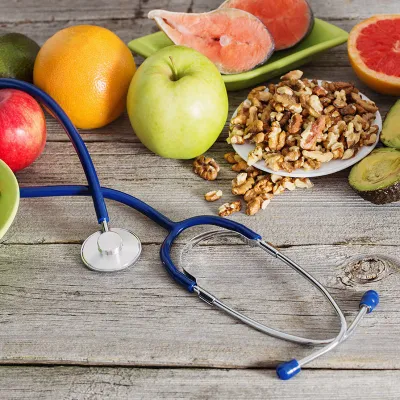 A spread of fruits and vegetables around a stethoscope on a wooden table