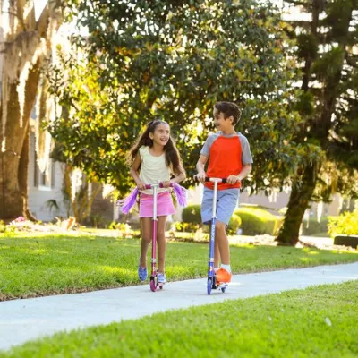 A brother and sister ride scooters through neighborhood