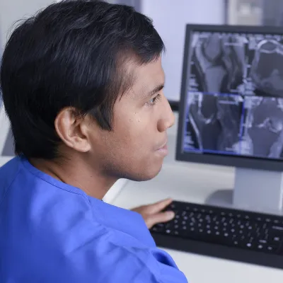 An Asian man examines imaging results on a computer.
