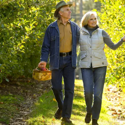 Elderly couple walking through a vineyard holding a basket.