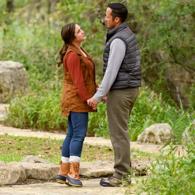 Couple standing and holding hands on a path in the forest.