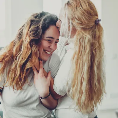 A mother kisses her teenage daughter.
