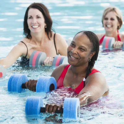 Three women building knee strength in a water aerobics class.