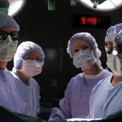 Doctor and staff in an Operating Room, facing camera, ready for surgery