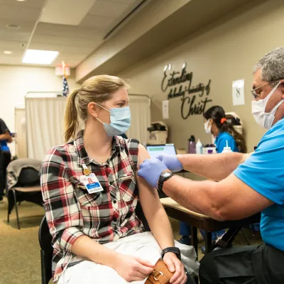 Female AdventHealth employee receives Moderna vaccine from male employee