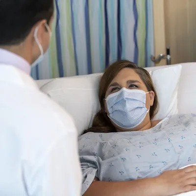 Dr. Bello talks with bariatric patient wearing a mask
