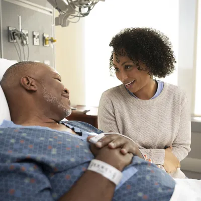 Family member comforting patient in hospital bed.
