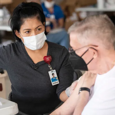 AdventHealth employee talks to an elderly man receiving a coronavirus vaccination