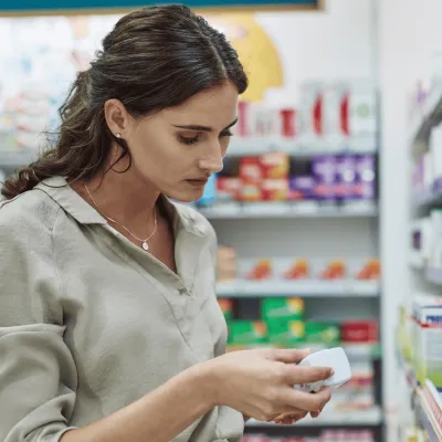 A woman reading the label of medication in a drugstore.