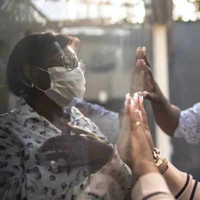 A family visiting a quarantined loved one through a window. 