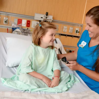 A girl smiles with her nurse