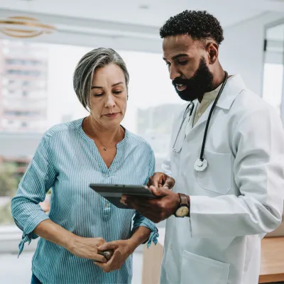 An older woman reviews test results on a tablet with her physician.