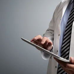A doctor takes notes on a tablet.