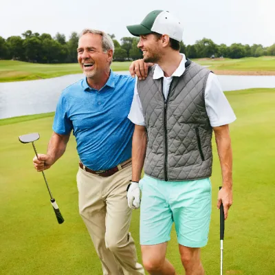 Two grown men walking away from a golf hole