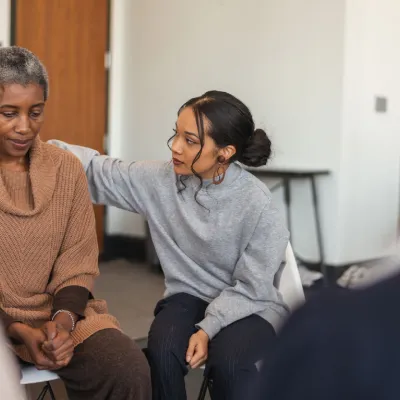 A young woman comforting an older woman in a support group