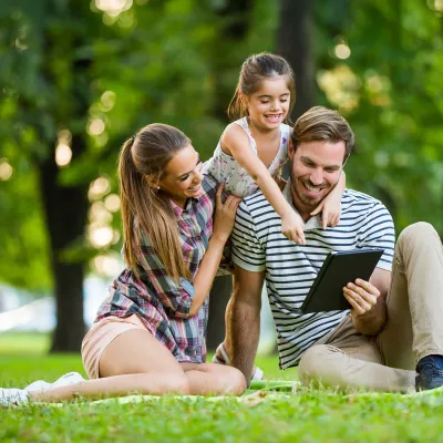Family Sitting in a Park Looking at a Tablet