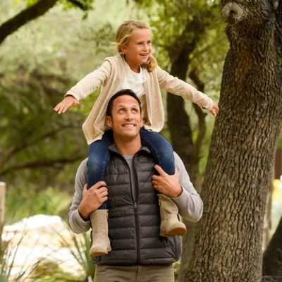 A girl sits on her dad's shoulders