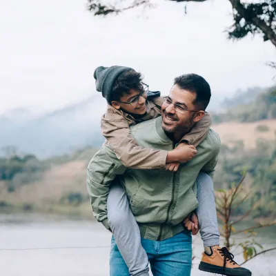 A father carrying his son on his back while hiking in the mountains