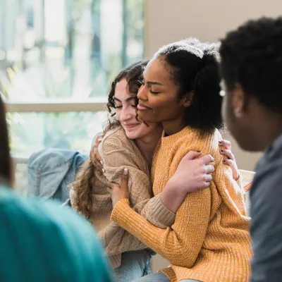 Two Women Happily Embrace After a Group Discussion