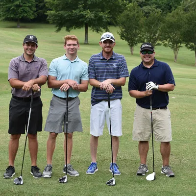 Group of golfers standing with golf clubs in hand.