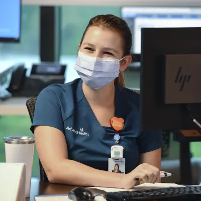 An AdventHealth employee working at a computer.