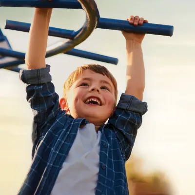 A little boy playing on the monkey bars