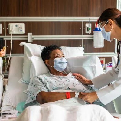 A physician comforting a patient of color