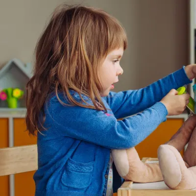 A child playing doctor with a stuffed animal.