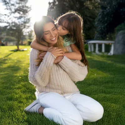Mother and daughter embracing in yard