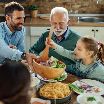 A family passing a salad at the dinner table.