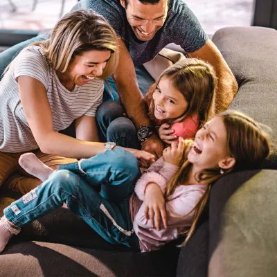 Happy family playing together on the couch.
