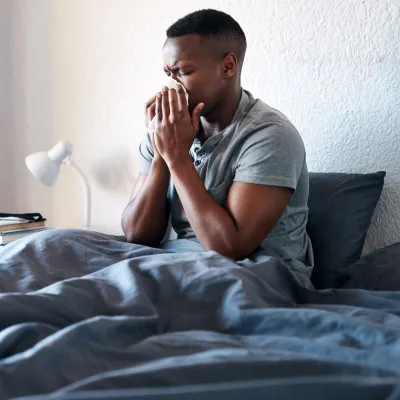 A man sneezing in bed.