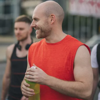 A man laughs with a group of friends after a workout.