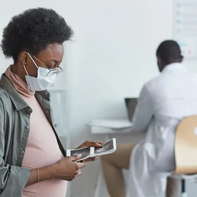 A pregnant woman looking at lab results in her doctor's office