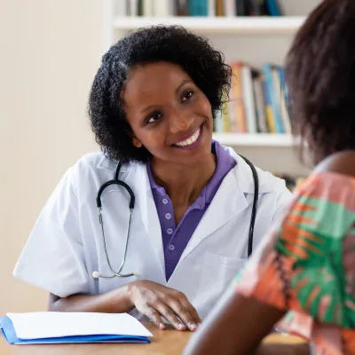 A smiling doctor talking with a female patient.
