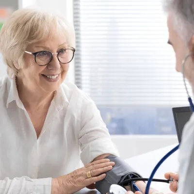 An older woman having her blood pressure checked by a doctor.