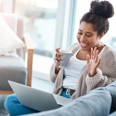 A woman waving to a friend on a video call.