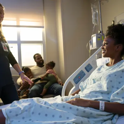 A nurse cares for a patient in a hospital room.