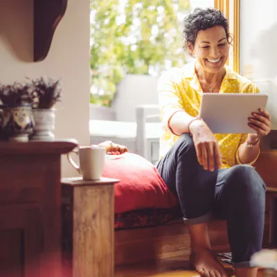 Middle-aged woman smiling at home with tablet