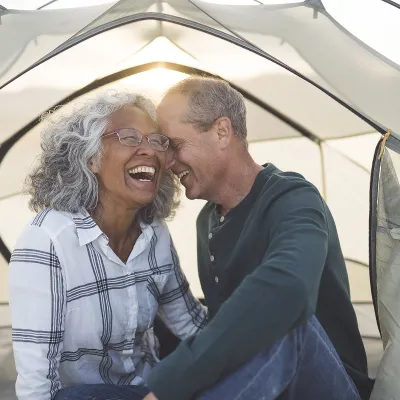 man and woman camping in tent with sun shining