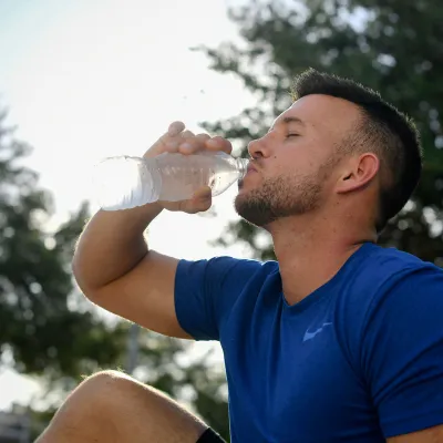 A young man drinking a water-bottle after exercising. 