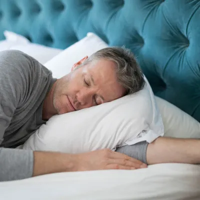 Man taking a nap in bed at home.
