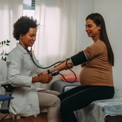 Pregnant woman getting her blood pressure checked by a physician.
