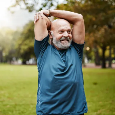 An older man stretching outdoors.