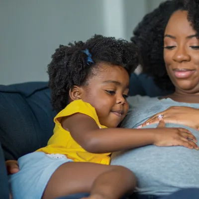Pregnant mother with toddler on couch.