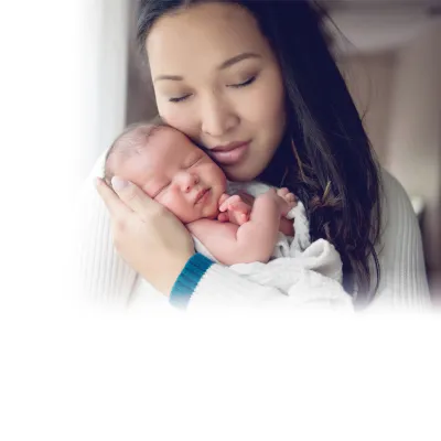 A young woman closing her eyes and holding her baby against her face.