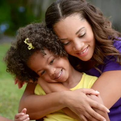 A mother hugs her daughter from behind. 