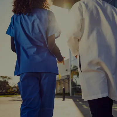 Two physicians at Florida Hospital Cancer Institute walk towards the hospital's front doors